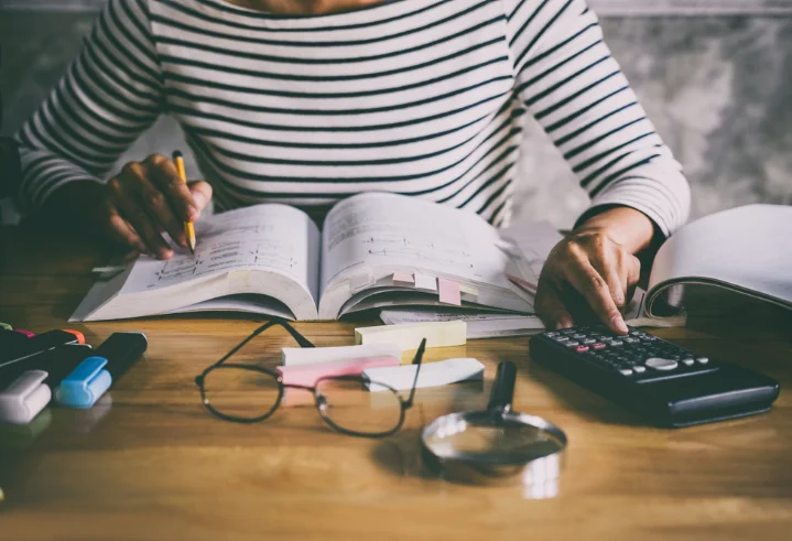 Educational Equipment - Student studying with books, calculator, and learning materials